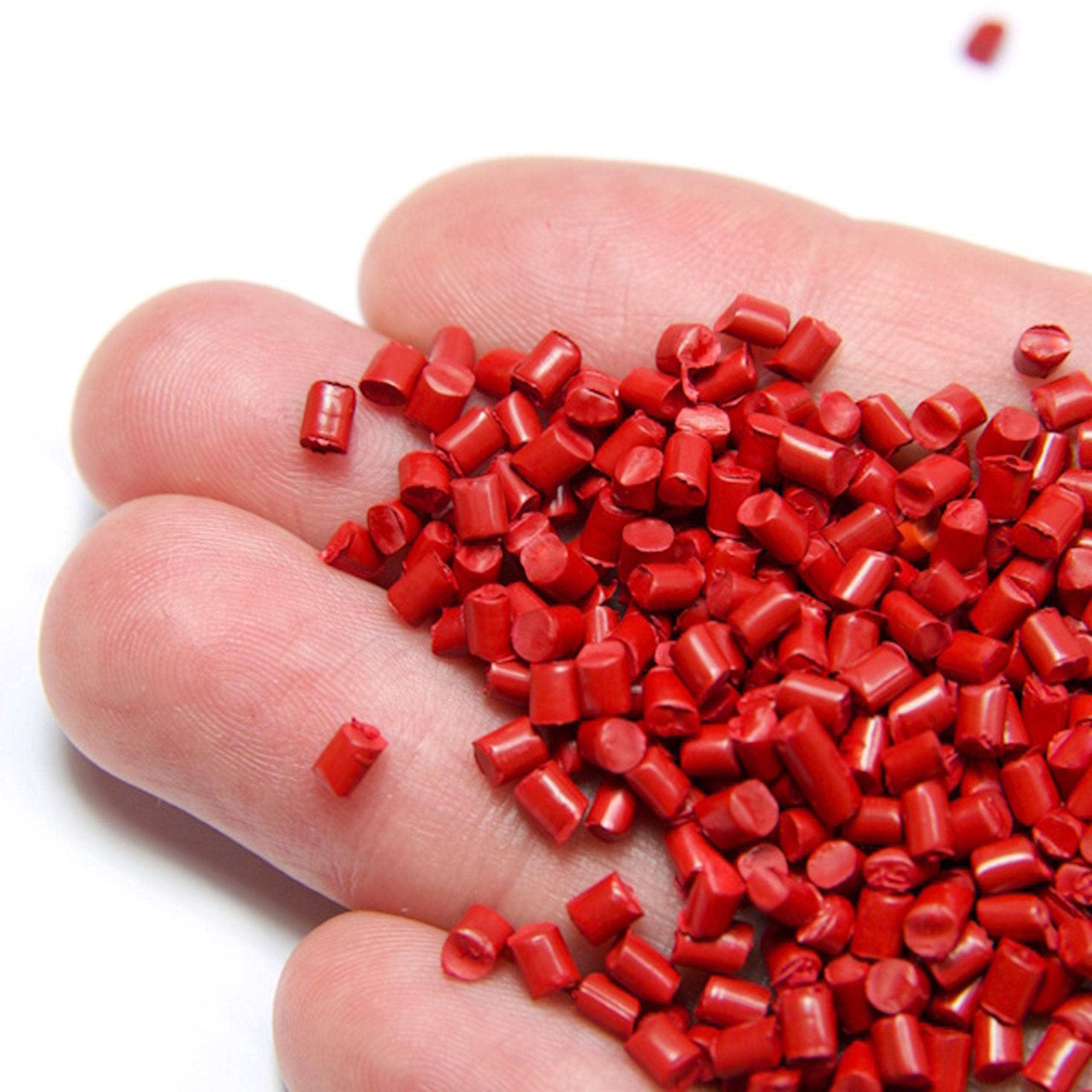 Red plastic polymer granules holding in hand