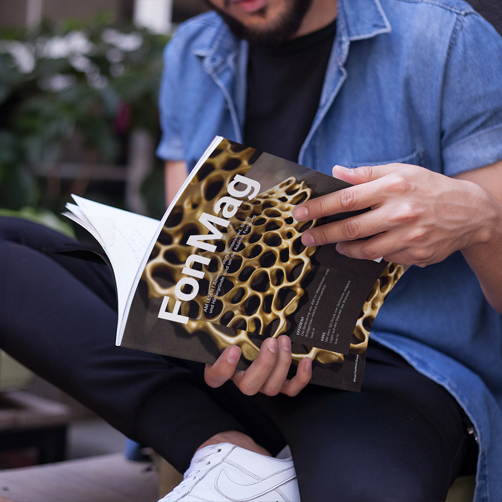 young-guy-reading-a-magazine-while-drinking-a-smoothie-in-a-cafe-outdoors-mockupa14456
